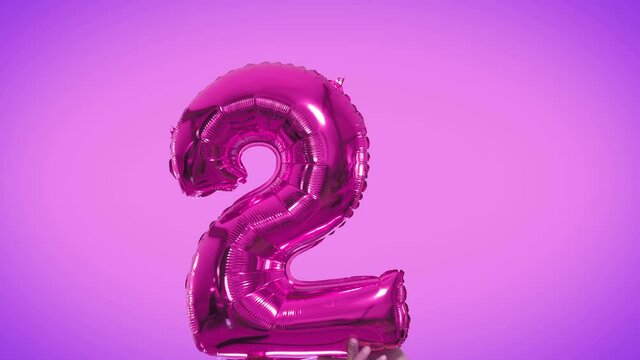 Gold. color foil number 2 two celebration balloon on a solid background.
Number 2 two years birthday anniversary gold balloons. Video is looped.