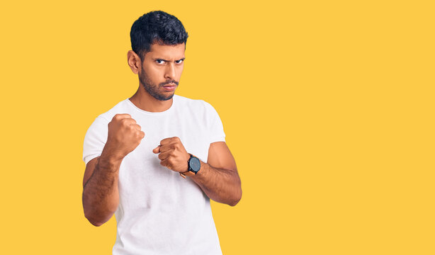 Young latin man wearing casual clothes ready to fight with fist defense gesture, angry and upset face, afraid of problem