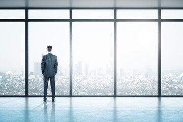 Young businessman looking on window in contemporary empty office
