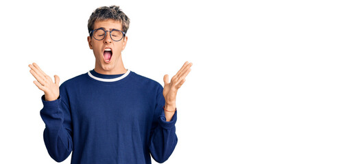 Young handsome man wearing casual clothes and glasses celebrating mad and crazy for success with...