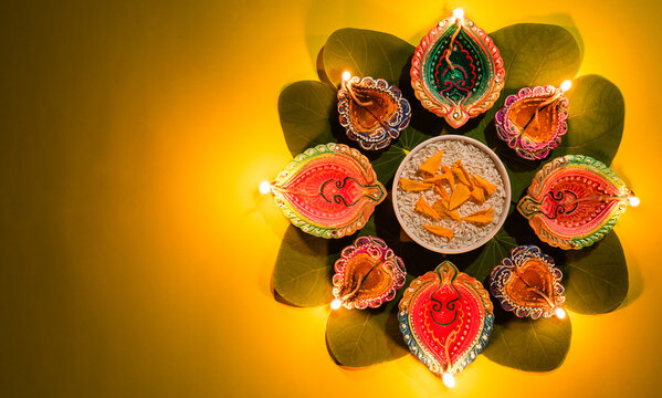 Happy Dussehra. Clay Diya lamps lit during Dussehra with yellow flowers, green leaf and rice. Dussehra Indian Festival concept.