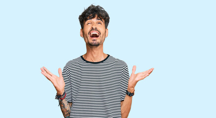 Young hispanic man wearing casual clothes celebrating mad and crazy for success with arms raised...