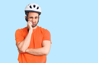 Young handsome man wearing bike helmet thinking looking tired and bored with depression problems with crossed arms.