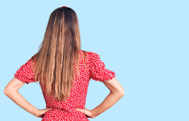 Young beautiful girl wearing dress and diadem standing backwards looking away with arms on body