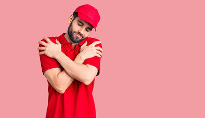 Fototapeta na wymiar Young handsome man with beard wearing delivery uniform hugging oneself happy and positive, smiling confident. self love and self care