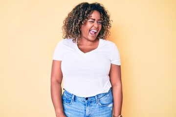 Young african american plus size woman wearing casual white tshirt winking looking at the camera with sexy expression, cheerful and happy face.