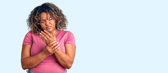 Young african american plus size woman wearing casual clothes suffering pain on hands and fingers,...