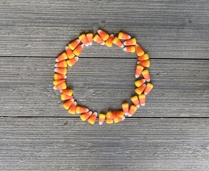 Fun Candy Corn Halloween Treats Circle Frame on Brown Wood Background Autumn Holiday Border Design for Advertisements, Banners, Seasons Greeting Cards, Sale Announcements and Party Invitations