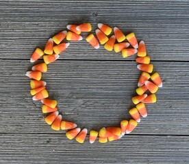 Circular Candy Corn Frame on Blank Wood Background with Copy Space for Advertisements, Sale Announcements, Banners, Seasons Greeting Cards and Halloween Party Invitations