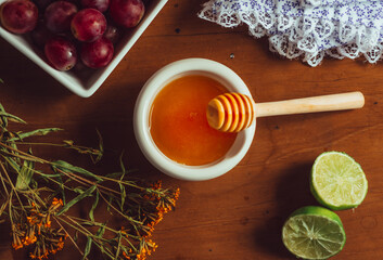 Overhead photograph of still life of organic food, honey, grapes and flowers. Cold remedy, honey and lemon
