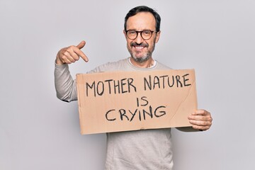 Middle age man asking for environment holding banner with mother nature is crying message smiling happy pointing with hand and finger