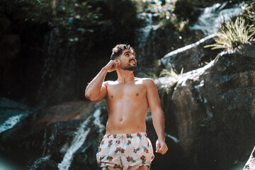 Chico atractivo con cascadas de fondo