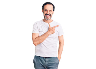Middle age handsome man wearing casual t-shirt cheerful with a smile on face pointing with hand and finger up to the side with happy and natural expression