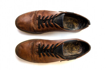Old dirty brown leather shoes on an isolated white background. Concept, second hand, hard work,...