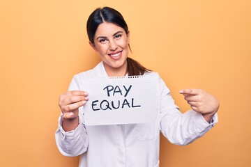 Young beautiful brunette psychologist woman holding paper with pay equal message smiling happy...