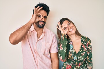 Beautiful young couple of boyfriend and girlfriend together doing ok gesture with hand smiling, eye looking through fingers with happy face.