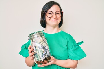 Brunette woman with down syndrome holding jar with savings winking looking at the camera with sexy expression, cheerful and happy face.