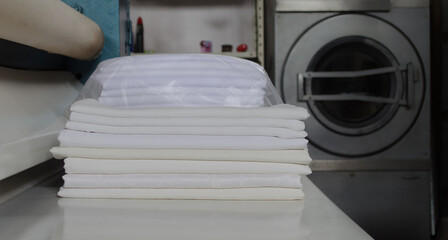 Stack of folded white fabrics in an industrial laundry.