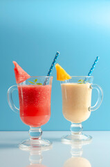 Watermelon and melon smoothies in a glass on colored background.