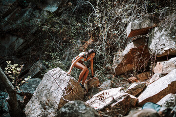 Chica joven atractiva en lago posando sobre una piedra