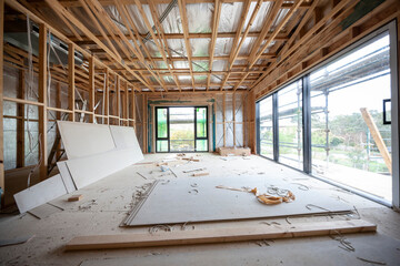 Interior view of a modern house undergoing construction, with timber frames, sliding glass doors...