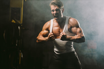 Powerful sexy muscular body model tearing shirt. muscular man showing muscles sweaty and furious in...