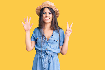 Brunette teenager girl wearing summer hat showing and pointing up with fingers number seven while...