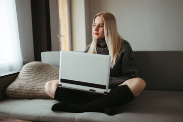 Young woman using laptop in cozy living room