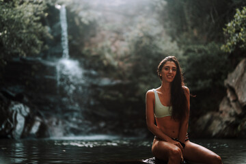 Fototapeta na wymiar Chica joven atractiva en lago posando sobre una piedra