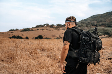 Joven explorador fotografo camina por medio de un valle seco en la naturaleza con su equipo fotografico
