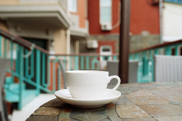white porcelain tea Cup on the table of street cafe with houses on the background