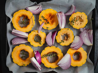Slices of delicata squash and red onions on a baking sheet.