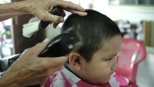 Asian boy having a haircut at hair salon.