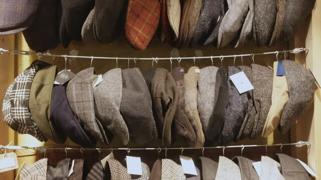 Large assortment of flat caps hanging on showcase in clothes shop. High quality FullHD footage