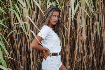 Chica veraniega morena en la playa naturaleza ca&ntilde;as de bambu con skateboard y bikini disfrutando de la hora dorada del atardecer