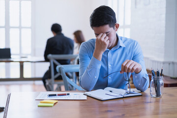 Fototapeta premium Young asian businessman feeling stressed and massaging his nose and keeping eyes closed. Tired frustrated, Business problem failure concept