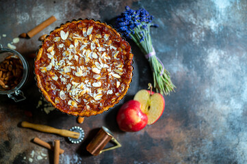 Apple pie, apple and lavender flowers on dark background. Copy space