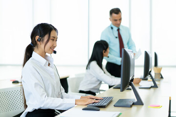 Smart young Asian and Caucasian ethnicity workers working in the office. Helpdesk and telemarketing sales representative team in working. Corporate call center team talking via using headset.