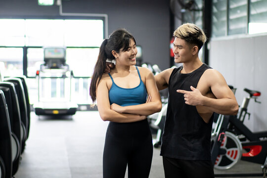 Cheerful healthy Asian sportspeople portrait in a gym with copyspace. Asian young sportswoman and sportsman posing for a photography in a indoor gym. Wellness and wellbeing in healthy people concept.