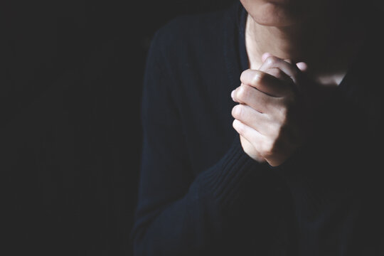 Christian woman praying worship hands with faith in religion and belief in God on dark background.