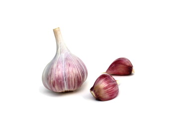 Garlic stands on a white background and small cloves nearby