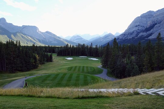 Gorgeous par 3 on a golf course surrounded by forest and big mountains in the background, on a beautiful sunny day in Kananaskis, Alberta, Canada.