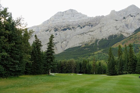 Gorgeous par 4 on a golf course surrounded by forest and big mountains in the background, on a beautiful sunny day in Kananaskis, Alberta, Canada.