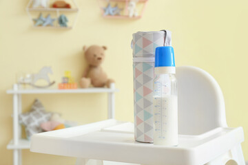 Bottle of milk for baby on high chair in room