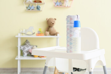 Bottle of milk for baby on high chair in room