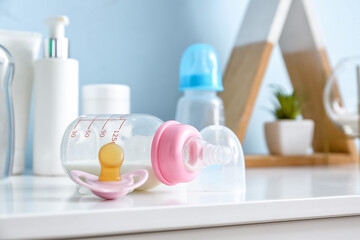 Bottle of milk for baby with pacifier on table