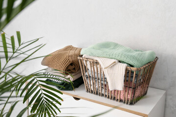 Basket with clothes on chest of drawers in room