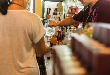 Man in face shield pouring fresh juice into plastice glass for customer in cafe.