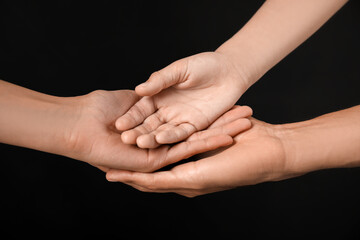 Hands of family on dark background