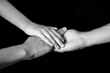 Hands of family on dark background